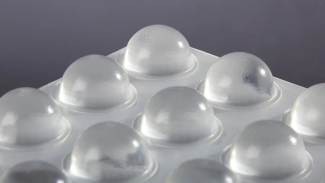 A close up of clear domed bumper feet on an adhesive backed sheet