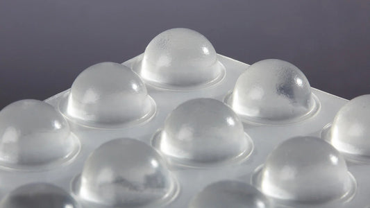 A close up of clear domed bumper feet on an adhesive backed sheet
